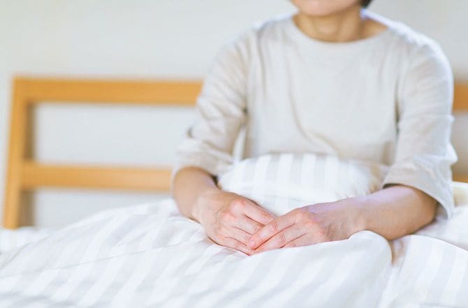 ベッドで上半身を起こしている人のイメージ