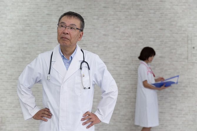 尊大な態度を取る医師、離れて歩く女性医療従事者