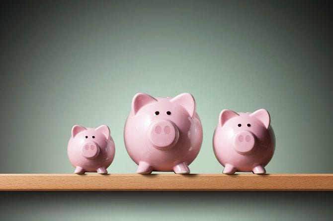 棚の上に置かれた3つのピンクの豚型の貯金箱