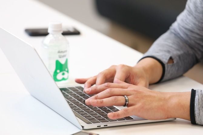 ノートパソコンで作業する結婚指輪をした手