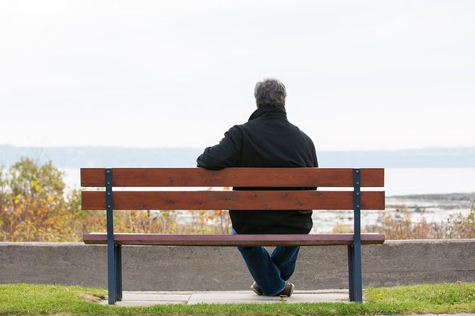シニア男性がベンチに座り川を一望します
