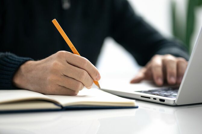 ノートにメモを書いている男性