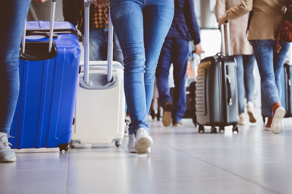 スーツケースをひいて空港内を移動する人々
