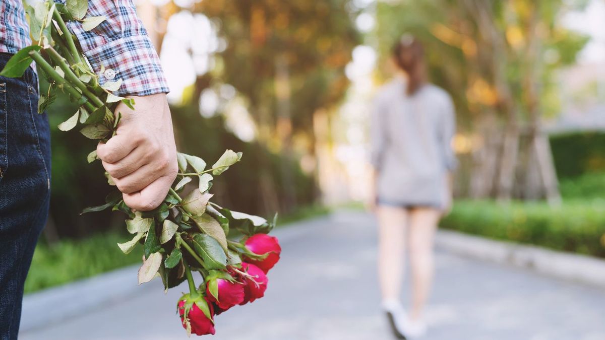 去っていく彼女の後姿とバラの花束を手に立ち尽くす男性