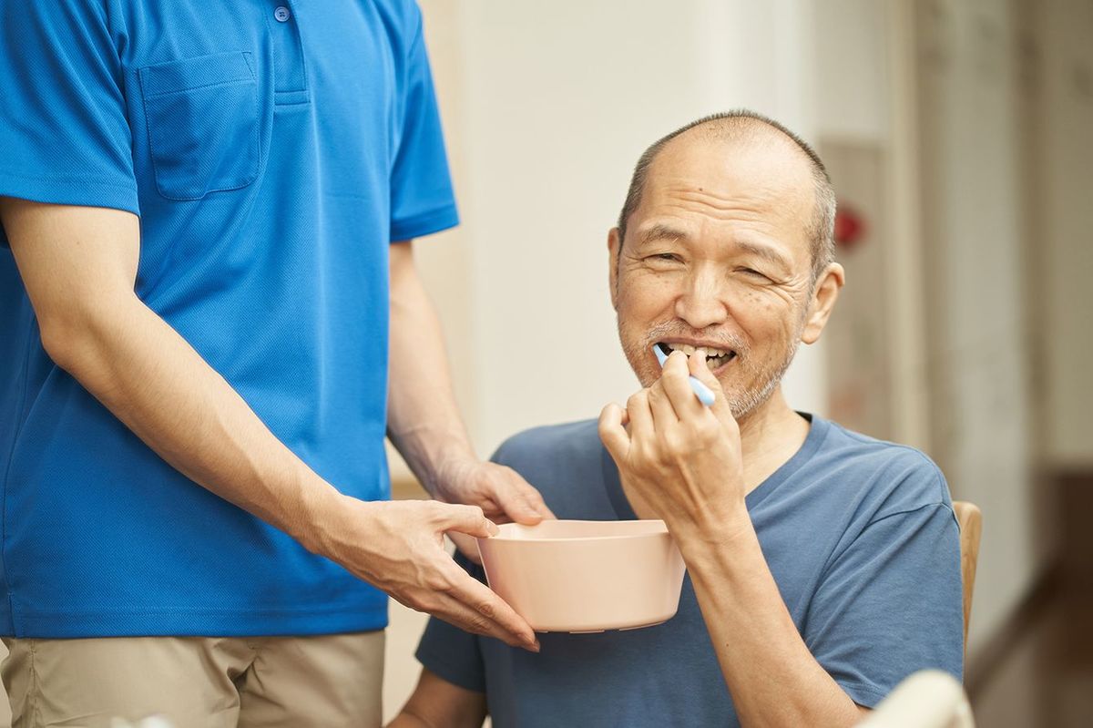 口腔の世話をする介護者と高齢者