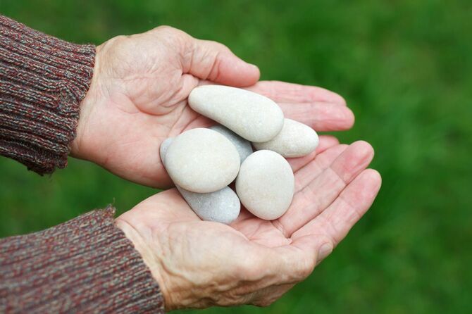 丸い石を手に持つ老人