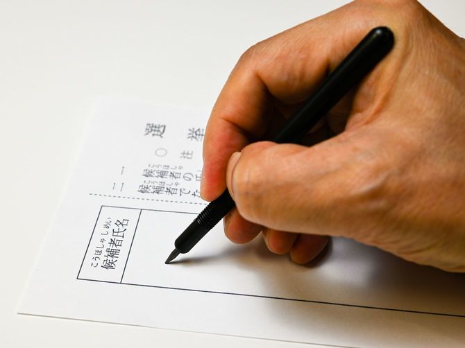投票用紙に候補者名を記入する手元