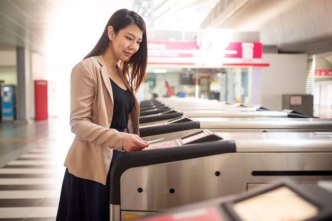 地下鉄のゲートでスマートカードで公共交通費を支払うフォーマルなビジネススーツを着ている若いアジアの女性