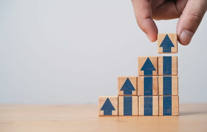 矢印の書かれた木製ブロックを積み上げていく手