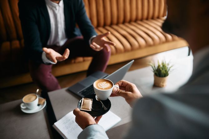 コーヒーを飲みながら話すビジネスマン