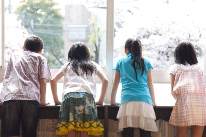 窓から校庭をのぞき込んでいる子供たち