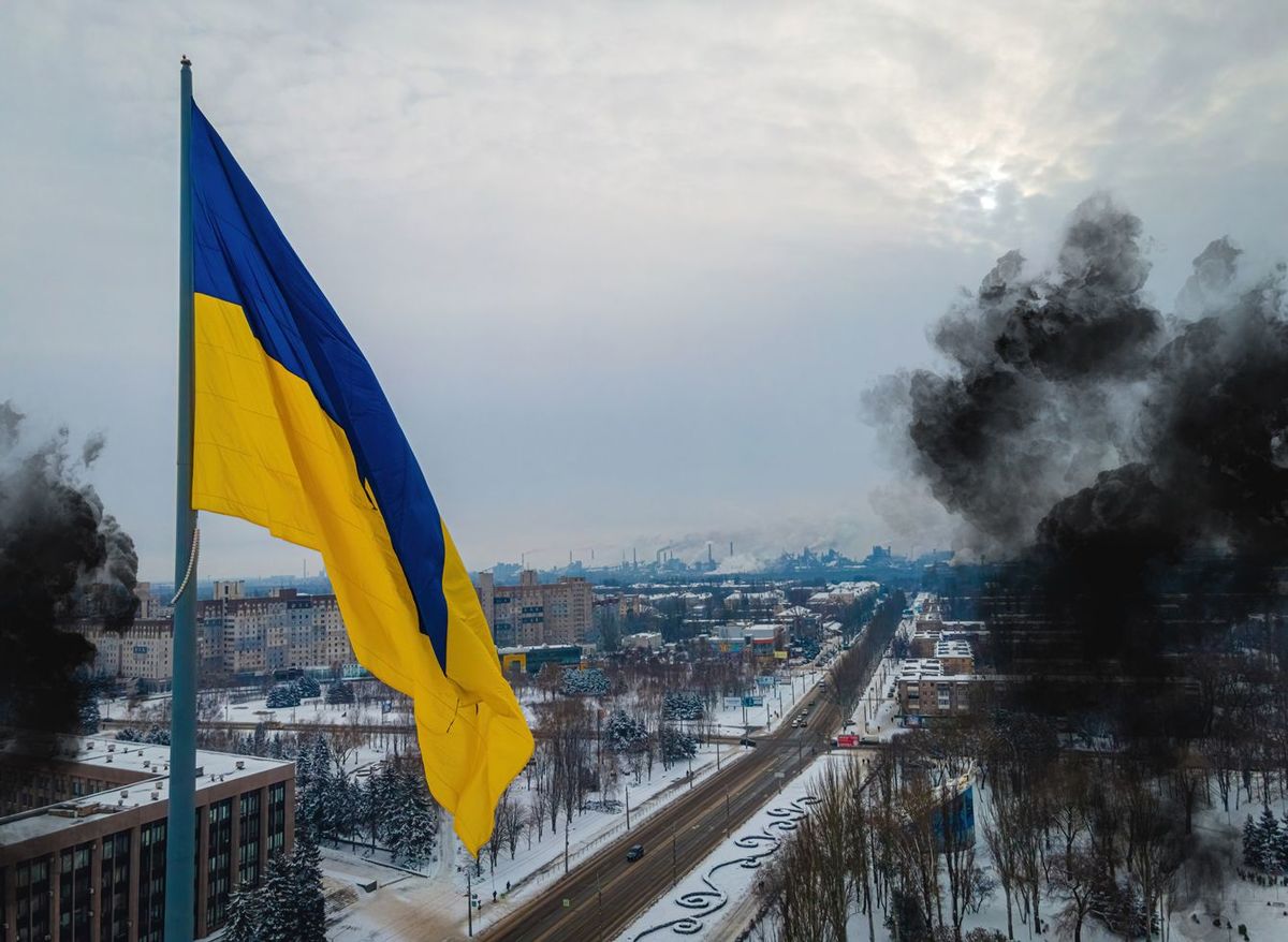 黒い煙がもうもうと立ち上げる街に掲げられたウクライナ国旗