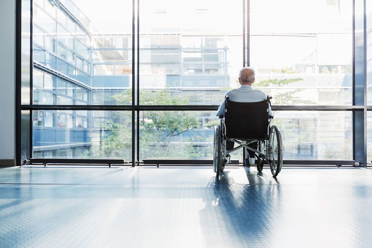 病院の廊下で窓の外を見ている車椅子の高齢者
