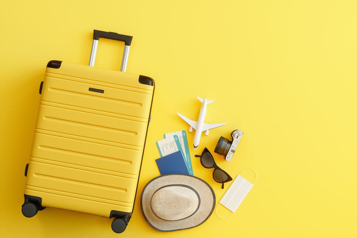 スーツケースと航空券、ハット、サングラス、カメラに不織布マスク