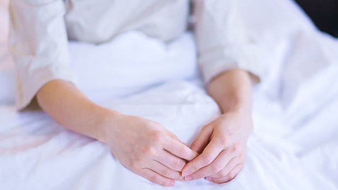 ベッドの上に体を起こす女性