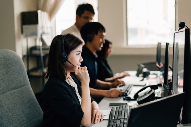 コンピュータを使用しながらヘッドセットを身に着けているビジネスウーマン