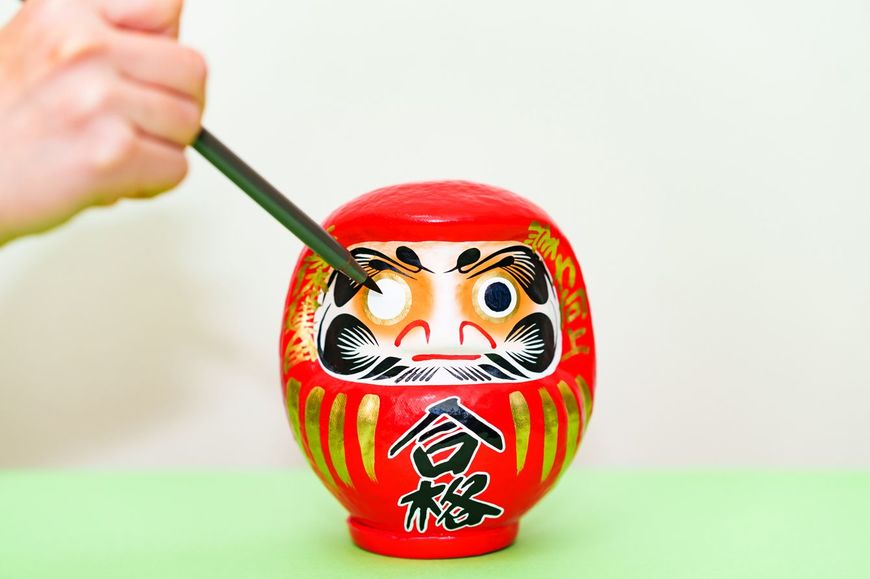 合格祈願のだるまに目を入れる手元