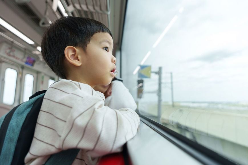 電車の窓から外を眺める子ども