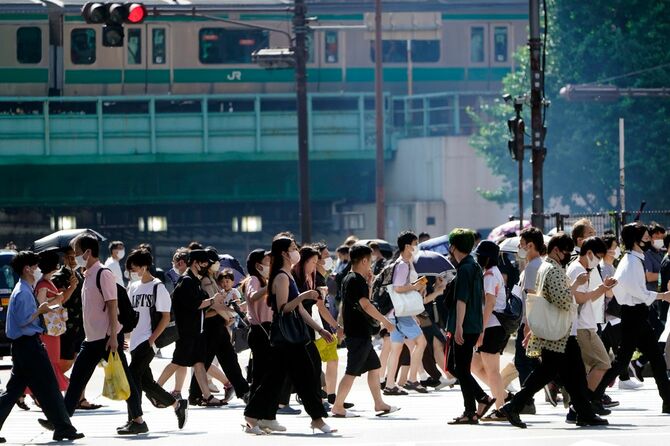 強い日差しの下、繁華街を歩く人たち。東京都は2022年7月9日、新たに9716人の新型コロナウイルス感染が確認されたと発表。1週間前から6100人増え、22日連続で前週の同じ曜日を上回った（東京都新宿区）