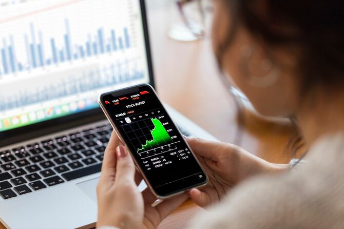 スマートフォンで金融チャートを分析する若い投資家