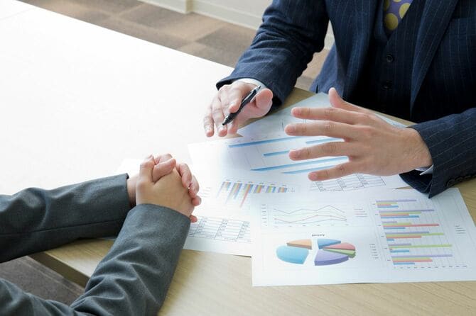 プリントした資料を用いて説明するビジネスマン