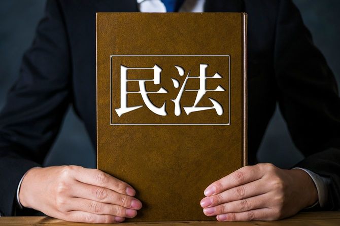 民法と書かれた本を持つ男性