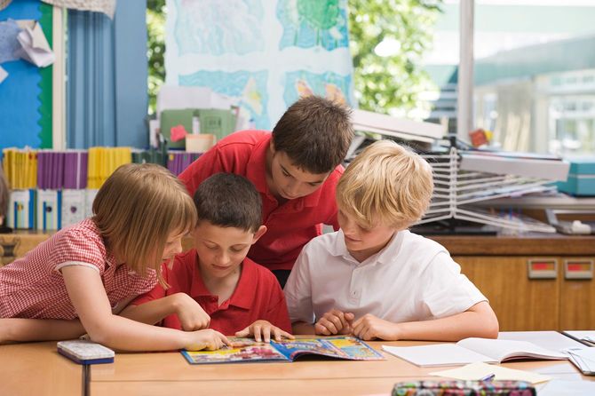 1冊の学習漫画を読んでいる4人の子どもたち