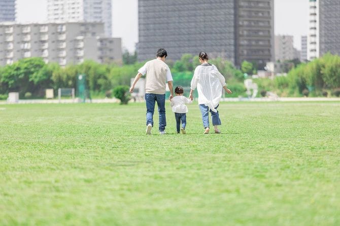手をつないで公園を歩く親子