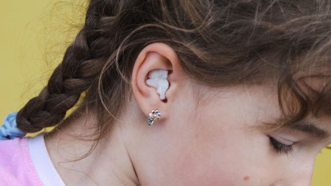 耳の片側を白い綿でふさいでいる女の子