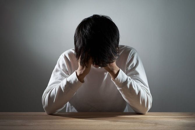 暗い部屋でうつ状態のアジア人男性