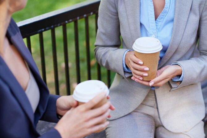 コーヒーを持って話す二人のビジネスウーマン