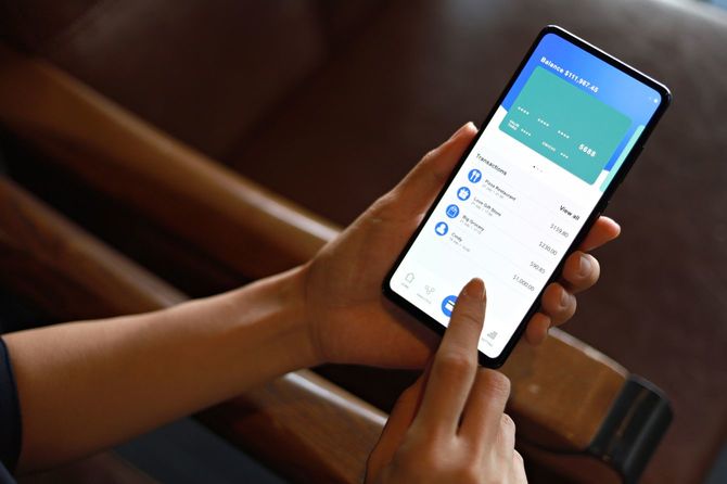 スマートフォン上のオンラインバンキングモバイルアプリの画面を開いている人の手元