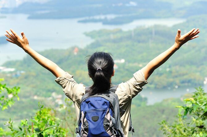 山頂から景色を眺め手をひろげる女性