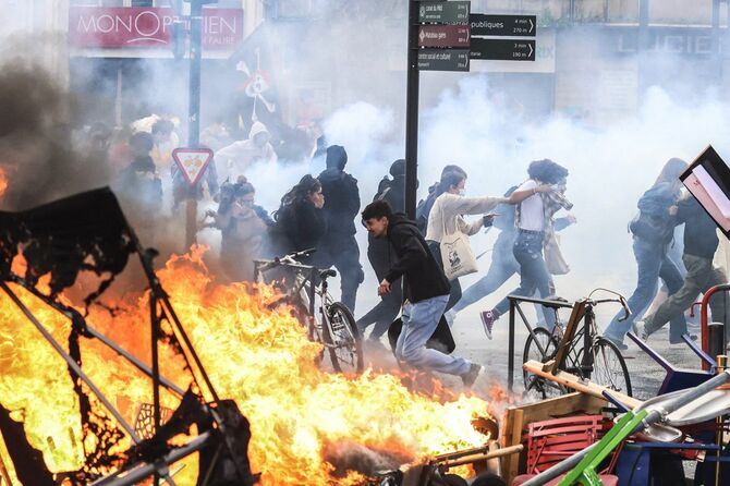 2023年3月23日、仏南西部トゥールーズで行われた抗議デモで、催涙ガスの中を逃げる参加者（フランス・トゥールーズ）