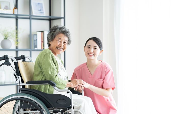 車椅子の高齢女性と若い女性介護者