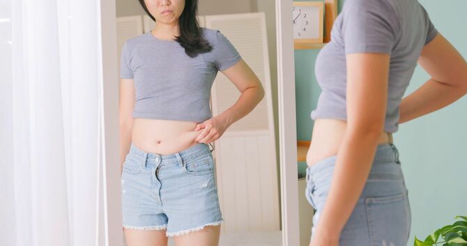 鏡でお腹を見る女性