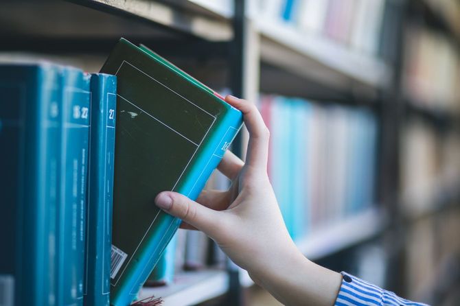 本棚から本を選ぶ女の手