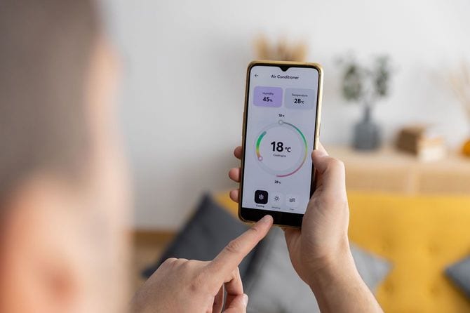 スマートフォンアプリで自宅のエアコンを調整する人