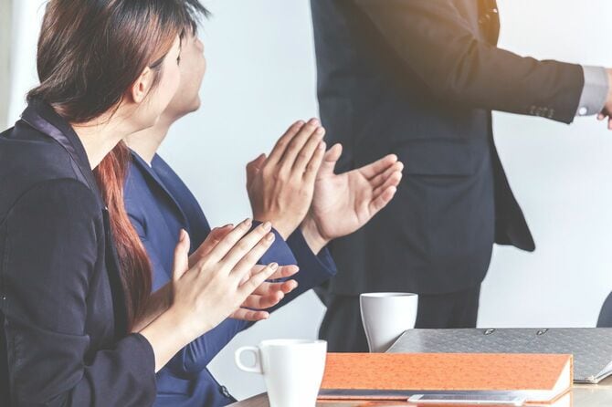 会議室で拍手を送るビジネスパーソンたち