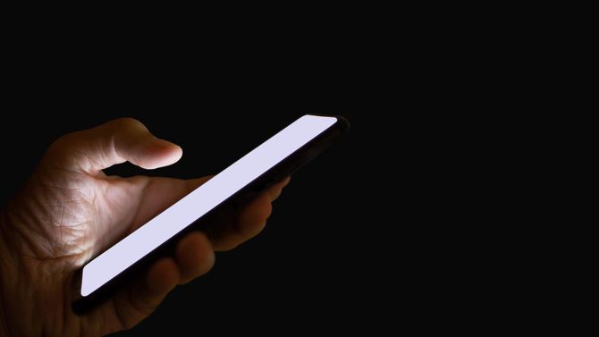 暗がりでスマホを操作する手元