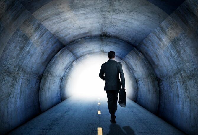トンネルの終わりに向かって歩くビジネスマン