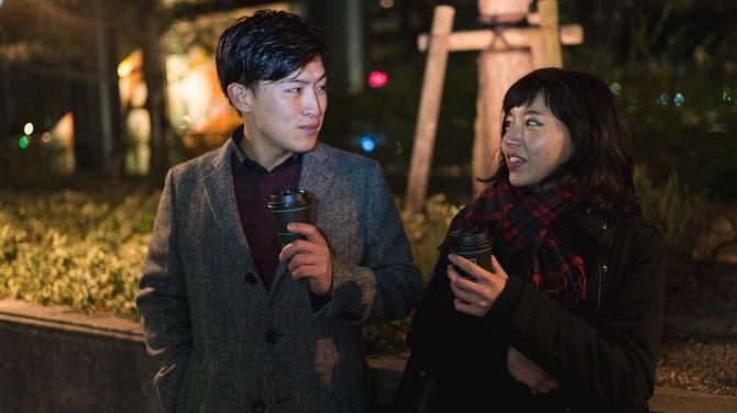 屋外でコーヒーを飲む男女