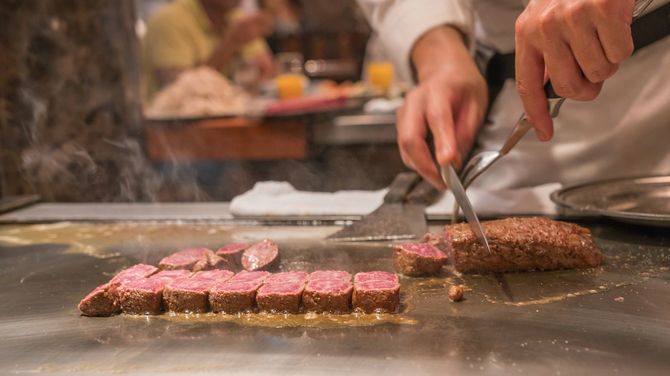 シェフの手で和牛ステーキがカットされている