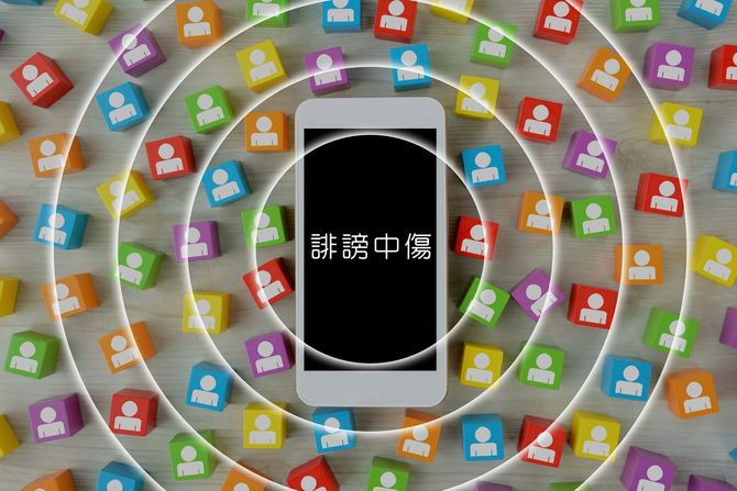 誹謗中傷と表示されたスマホ画面を同心円状に、広がる人型マーク
