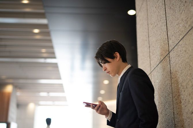 ホールの片隅でスマホに目を落とす新卒社員
