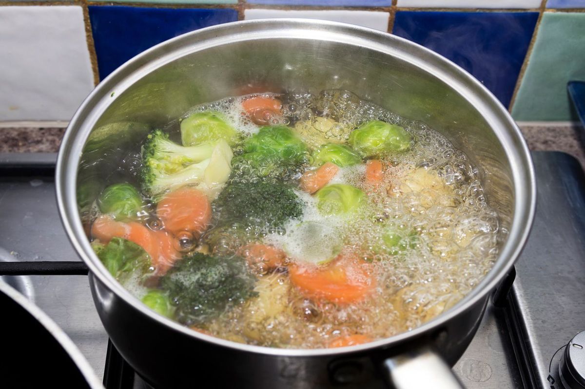 コンロ上の沸騰した鍋に入った野菜