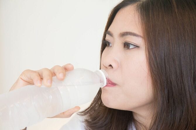 ペットボトルの水を飲む女性