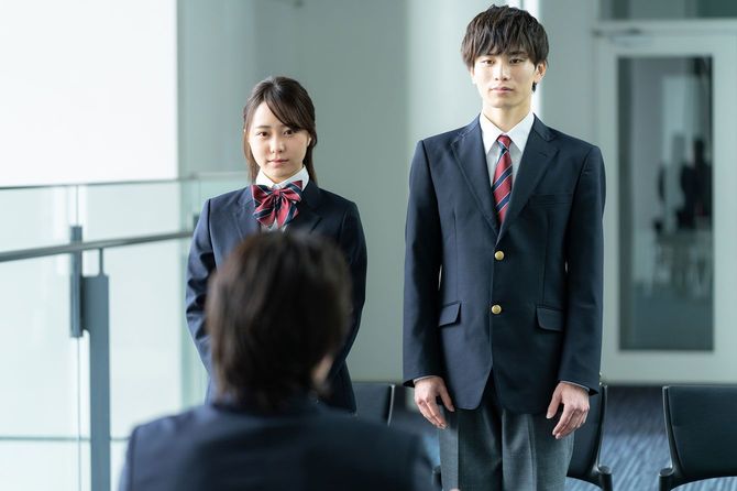 教師の前に立つ2人の生徒