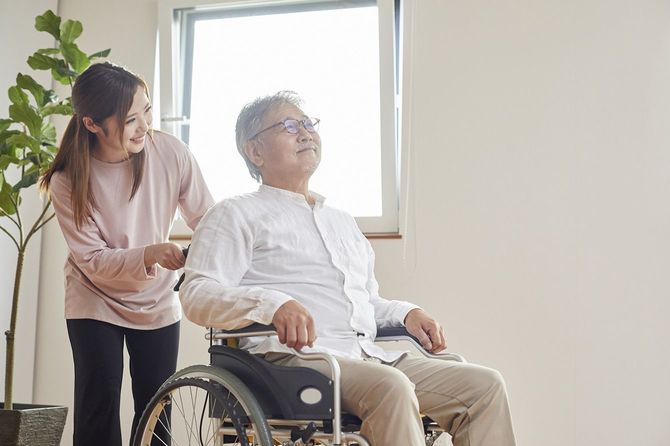 高齢男性が乗った車椅子を押す女性