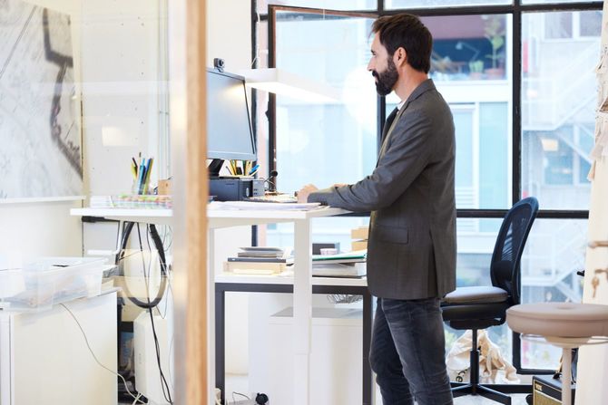 明るいオフィスのスタンディングデスクで働いている男性ビジネスマン